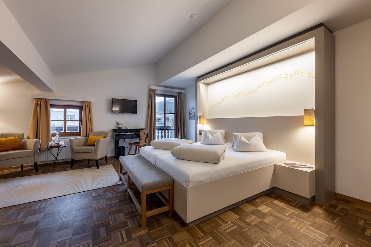 A modern hotel room with a large bed, a desk, and a TV.