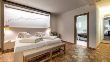 Un dormitorio moderno con cama, banca, mesitas de noche y una lámpara fijada a la pared.