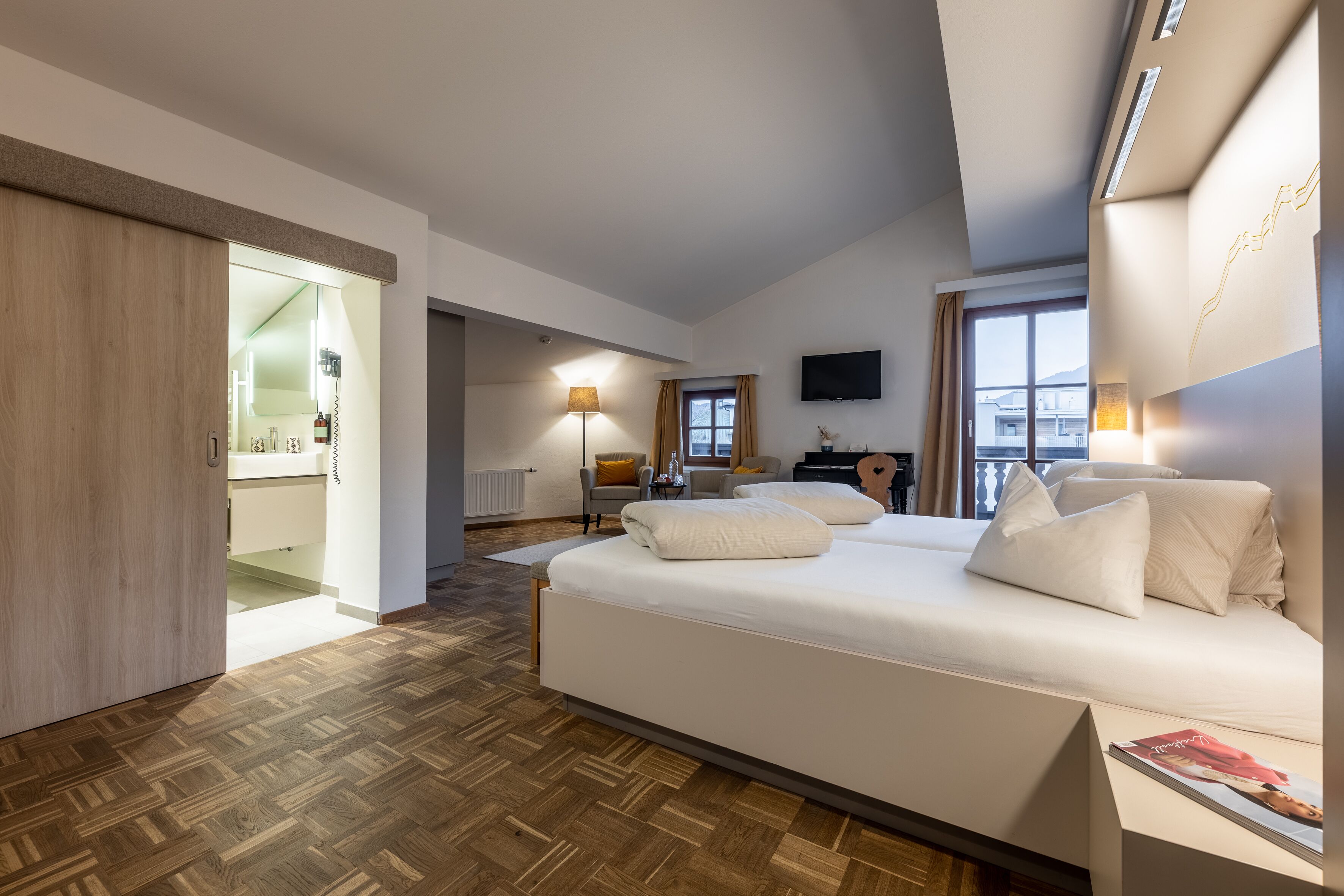 Habitación de hotel moderna con una cama grande, un escritorio, una silla y un televisor en la pared.