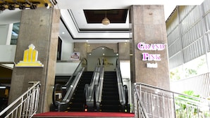 A hotel entrance with a sign reading "Grand Pink Hotel," featuring a red carpet, two escalators, and a modern interior design. - Grand Pink Hotel Hat Yai (Hat Yai)