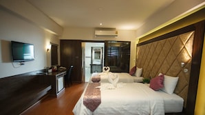 A hotel room with two beds, a TV, an air conditioning unit, and a desk with a computer. - Grand Pink Hotel Hat Yai (Hat Yai)
