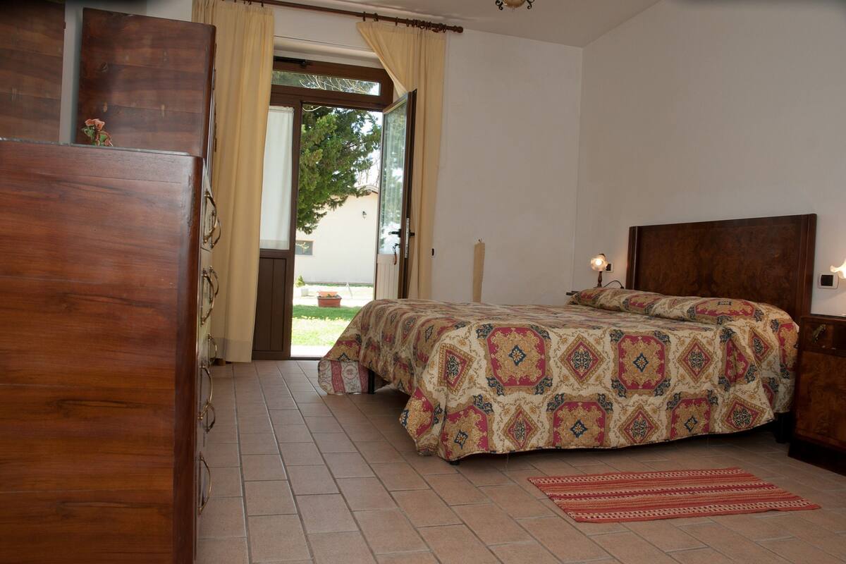 Une chambre à coucher avec un lit, une armoire en bois et une porte donnant sur un balcon.