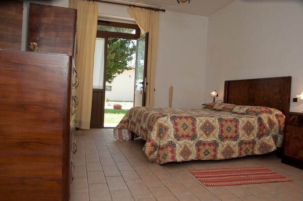 Un dormitorio con cama, armario de madera y puerta que da a un balcón.