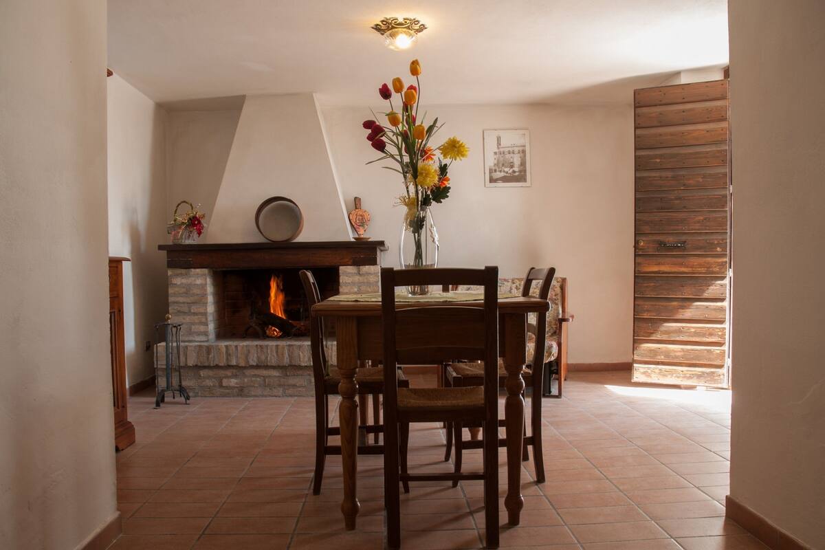 Un coin repas avec une cheminée, une table à manger en bois et des chaises.