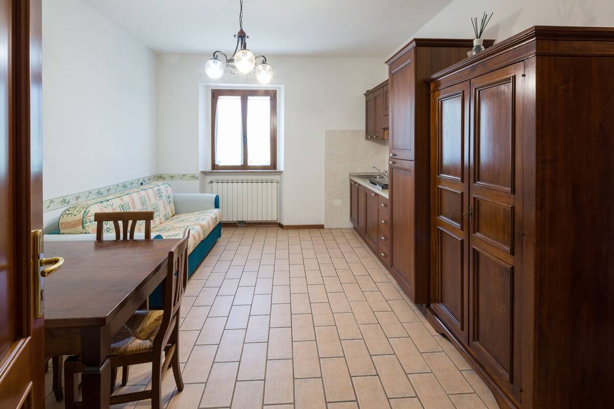 Une cuisine équipée d’une table à manger, de chaises, d’un canapé et de meubles de rangement en bois.