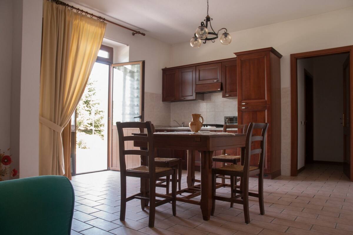 Une cuisine avec des meubles de rangement en bois, une table à manger et des chaises.