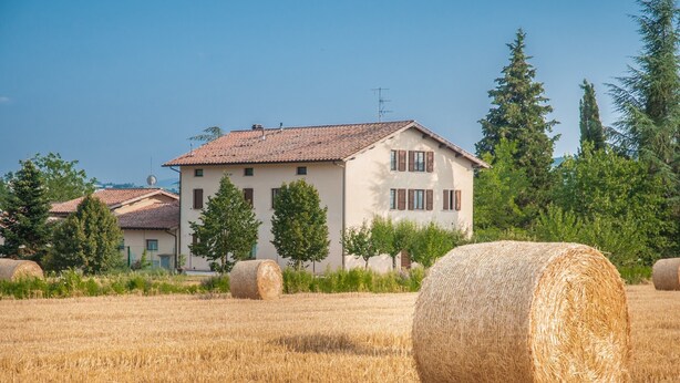 A rural setting with a house and hay bales in a field. - Agriturismo Casella del Piano (Gubbio)