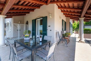 An outdoor patio with a glass table, chairs, and a bottle of wine. - La Rosa Gialla (Barolo)
