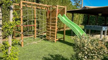 Children can play on the playground structure with a slide and a bench nearby.