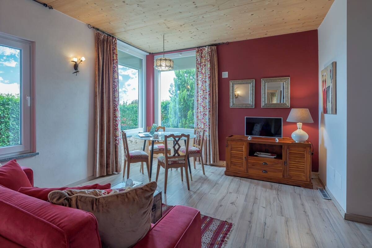 Una sala de estar con pared roja, techo de madera y un mueble de televisión con una lámpara.