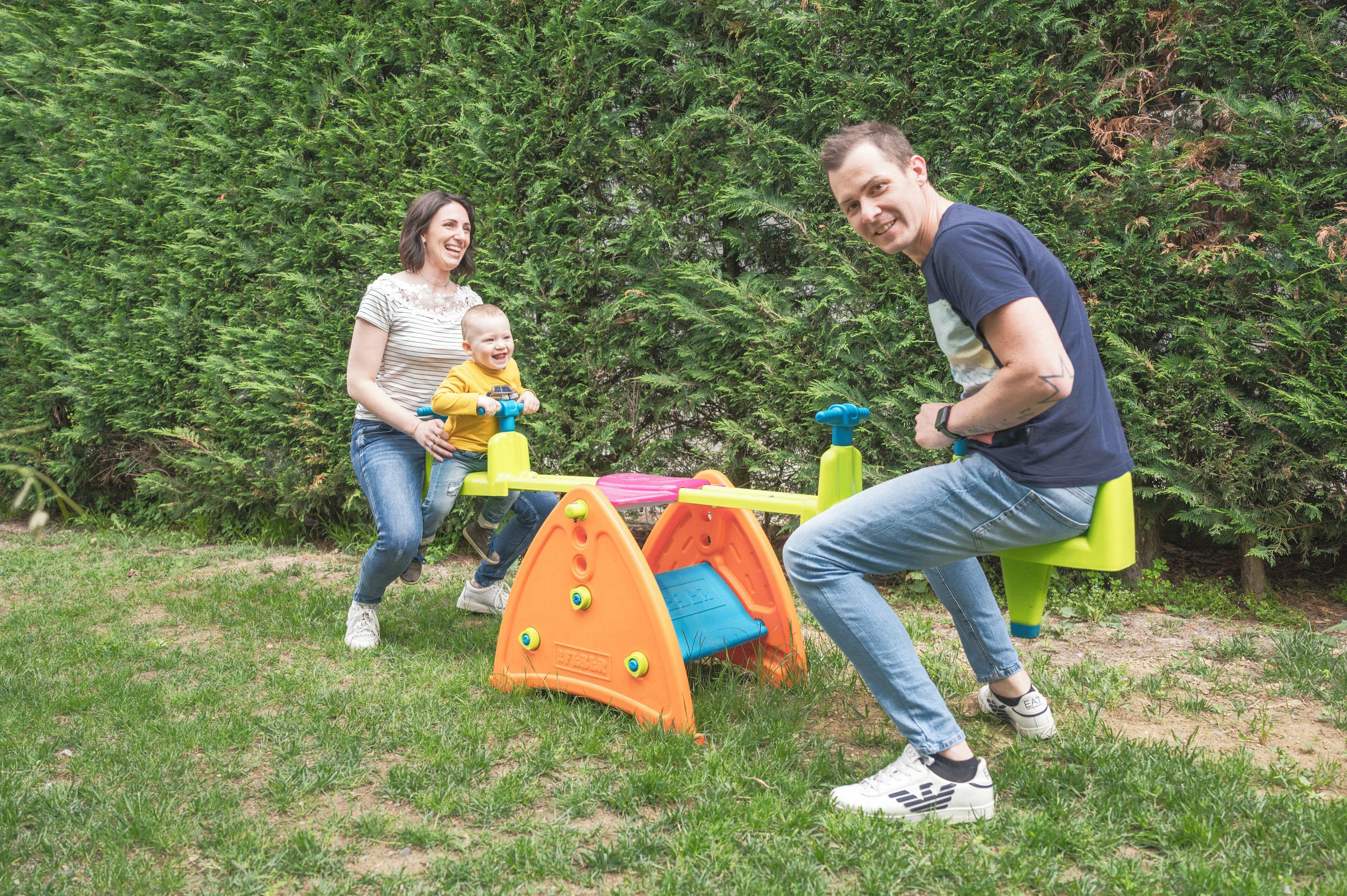Eine Familie spielt auf einem Spielplatz mit Rutsche und Klettergerüst.