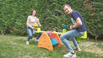 Eine Familie spielt auf einem Spielplatz mit Rutsche und Klettergerüst.