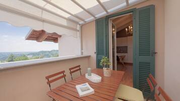 A balcony with a wooden table, chairs, a candle, and a potted plant.