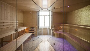 A sauna with wooden benches and a tiled floor, glass walls, and a tiled wall with a bench on the right. - OCA Flores Hotel Boutique (Porto)