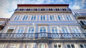 A building with a tiled facade, multiple windows, and a balcony with ornate railings. - OCA Flores Hotel Boutique (Porto)