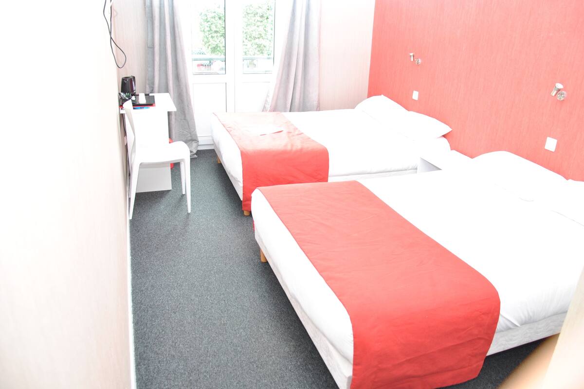 Une chambre d’hôtel avec deux lits, un bureau et une chaise.