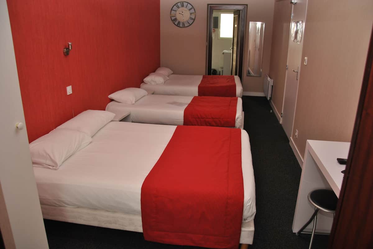 Une chambre d’hôtel avec trois lits, un bureau, un miroir et une horloge au mur.