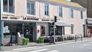 A building with a sign for 'BAR - HOTEL LA ROTONDE' and 'BRASSERIE - PIZZA'. There are outdoor seating areas with tables and chairs. - La Rotonde (Saint-Malo)