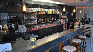 A bar area with a counter, stools, and shelves stocked with bottles and glasses. - La Rotonde (Saint-Malo)