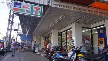 Una tienda 7-Eleven con entrada cubierta, una fila de motocicletas estacionadas y un cajero automático visible.