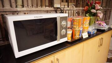A white Electrolux microwave on a black countertop with various food items and a vase of flowers.