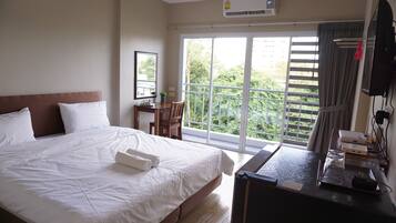 Una camera d'albergo con un letto grande, una scrivania, una sedia e vista sul verde dalla finestra.