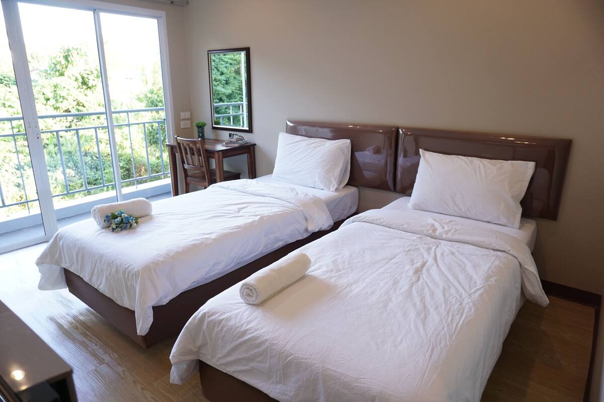 A hotel room with two beds, a desk, and a chair.