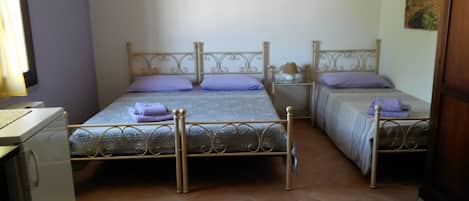 A bedroom with two beds, a desk, and a washing machine.