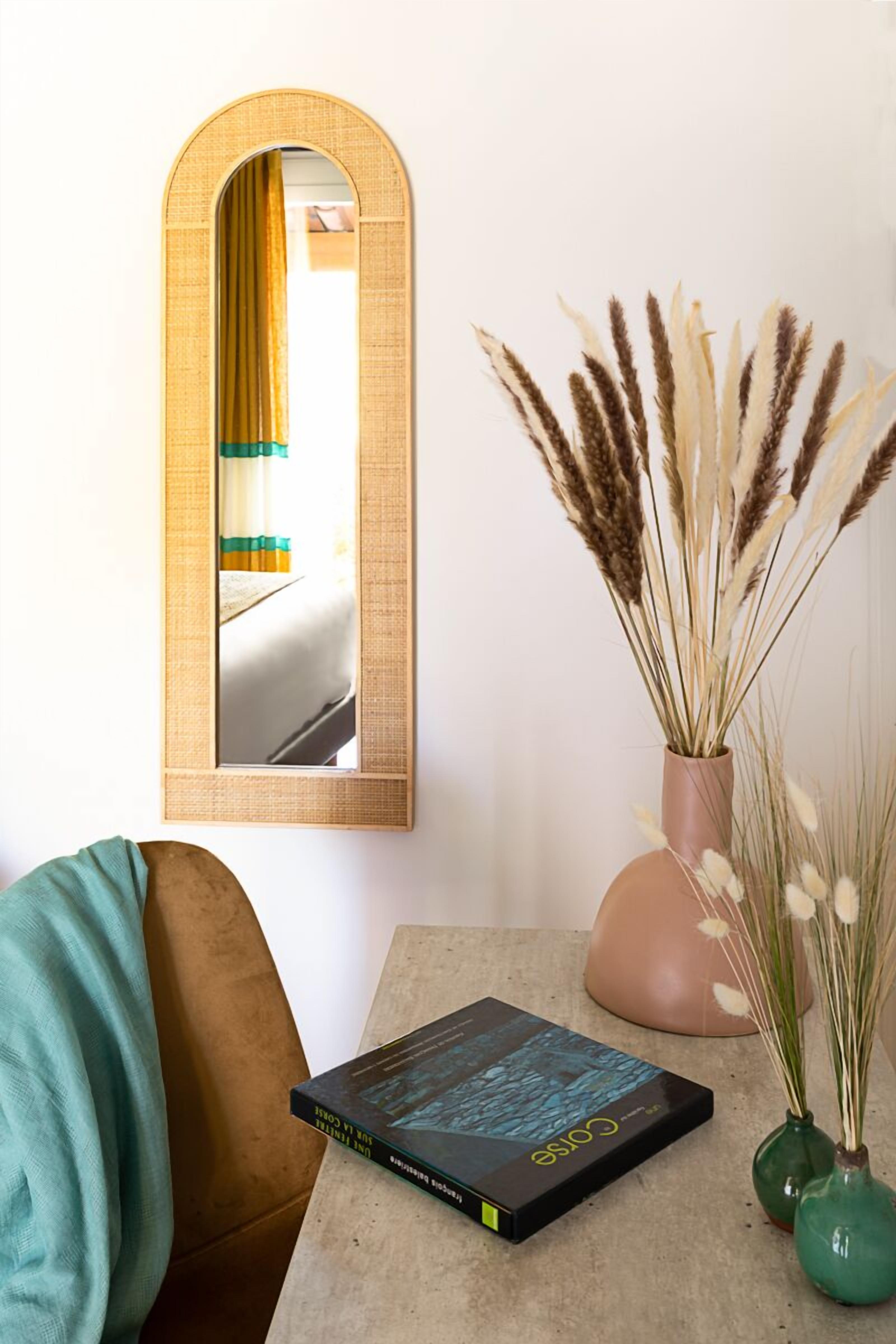 Een kamer met een spiegel, een boek en twee vazen met gedroogde planten.