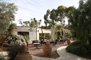 An outdoor patio area with tables and chairs, surrounded by potted plants and trees. - San Giovanni (Porto-Vecchio)