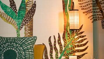A room with a bed, a nightstand, a lamp, and a wall with a nature-themed mural.