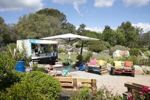 A food truck with a white canopy, surrounded by outdoor seating with various chairs and a table. - San Giovanni (Porto-Vecchio)