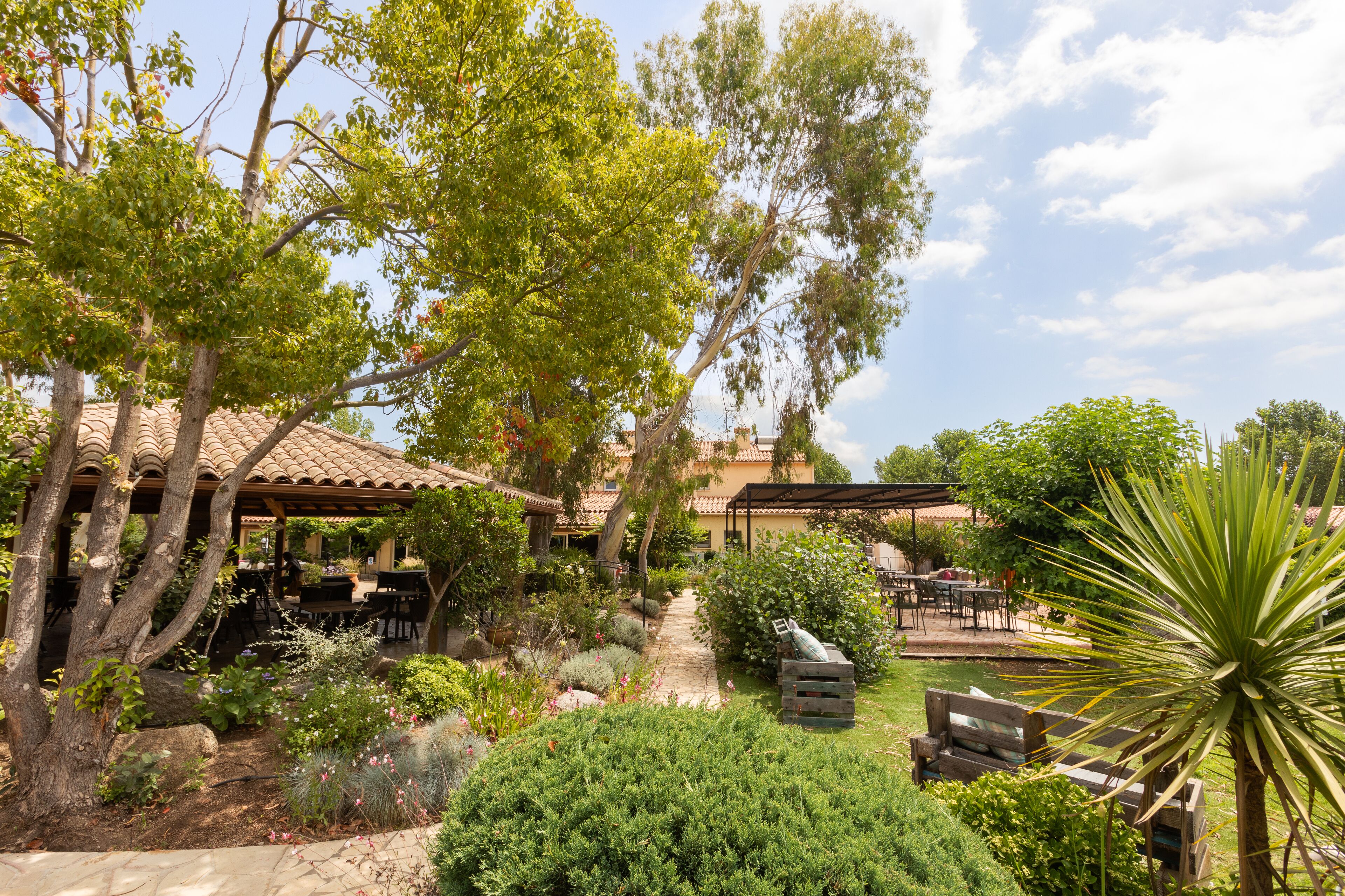 An outdoor patio area with a pergola, seating, and a garden path.