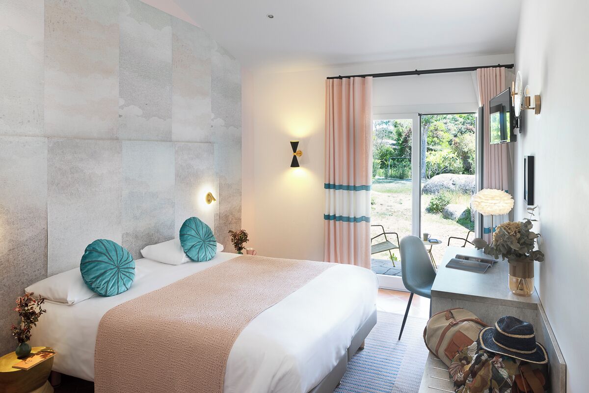 Ein modernes Schlafzimmer mit einem großen Bett, einem Schreibtisch mit Lampe und Blick ins Freie.