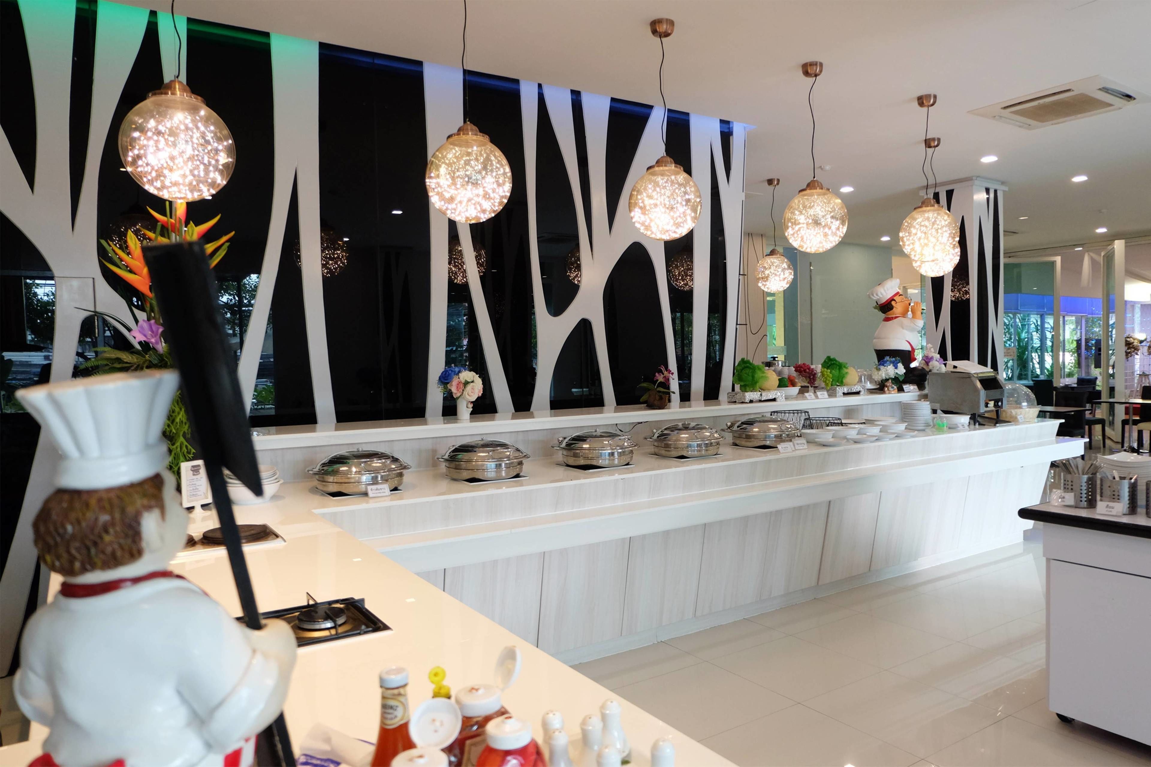 Eine moderne Hotelhalle mit einer zentralen Insellounge, einem Büfett, dekorativer Beleuchtung und einer Kochstatuette.