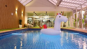 An indoor swimming pool with a large inflatable unicorn float. - Grand Hill Resort and Spa (Nakhon Sawan)