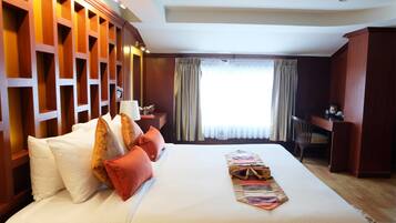 Habitación de hotel con una cama grande, un escritorio y una ventana con cortinas.