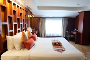 A hotel room with a large bed, a desk, and a window with curtains.