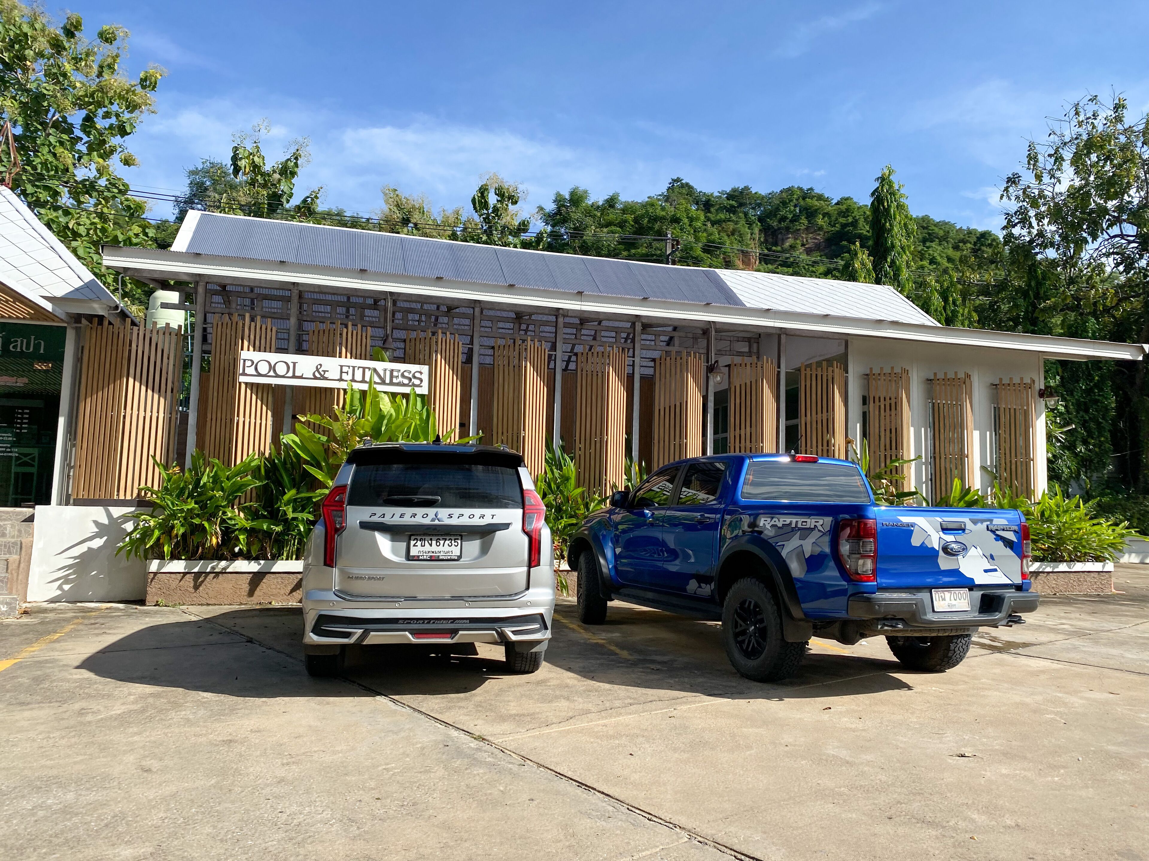 Two vehicles parked in front of a building with a sign reading "POOL & FITNESS".