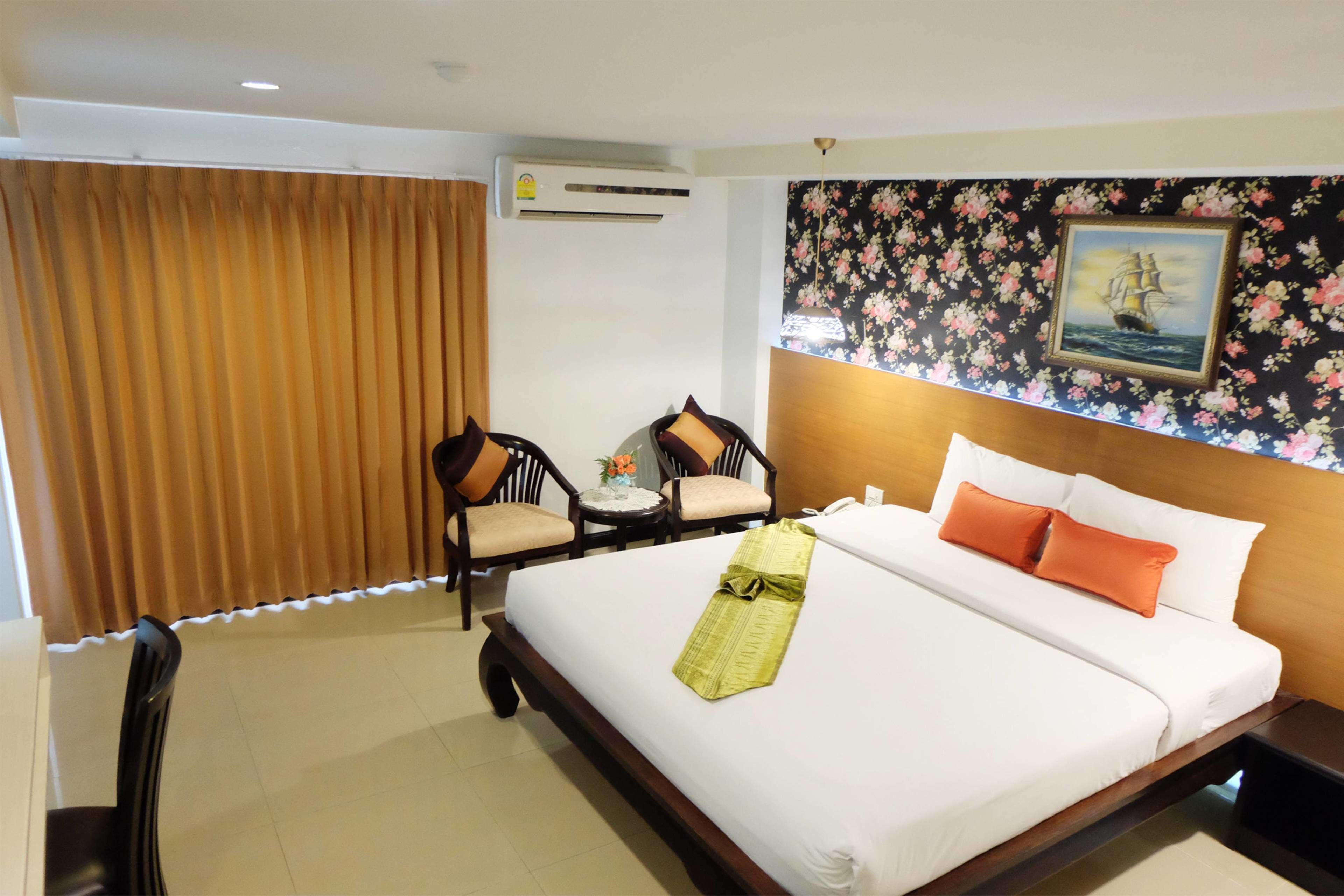 Habitación de hotel con una cama grande, dos sillas, una mesita y un cuadro en la pared.