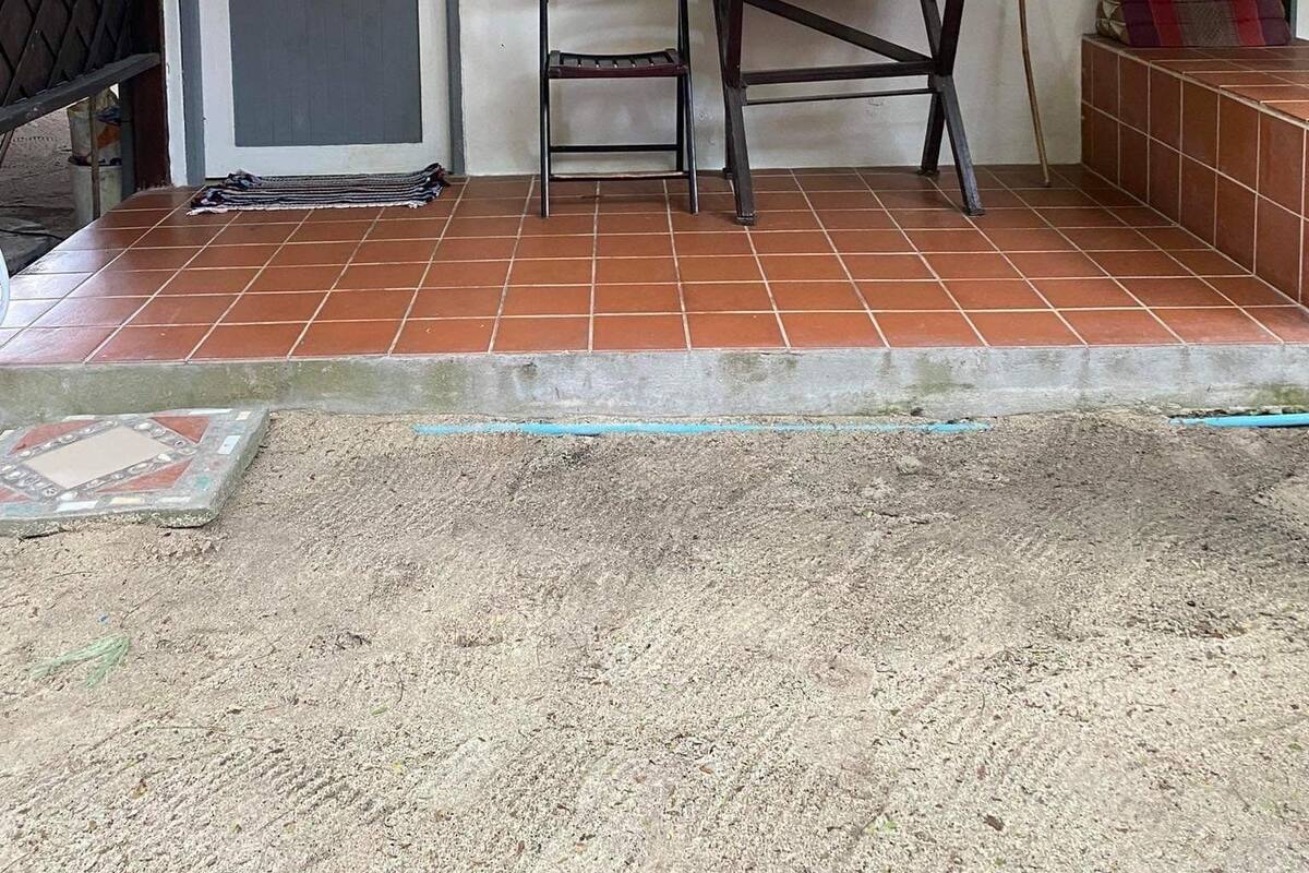 Une petite pièce avec un sol carrelé, une porte portant un numéro, une chaise, une table et une plante décorative.