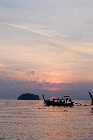 Ein Boot liegt in ruhigem Wasser vor einem Sonnenuntergang.