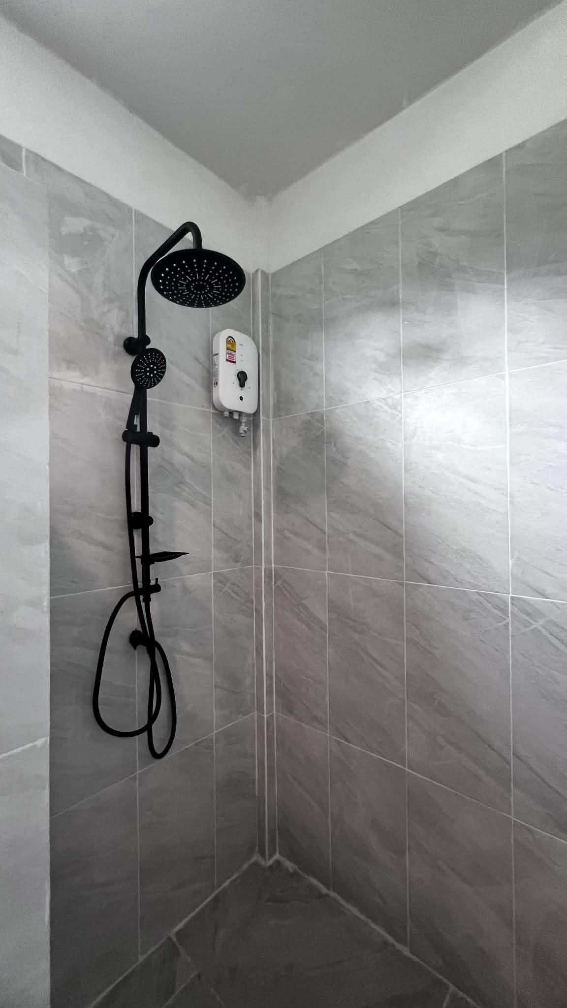 A shower with a handheld showerhead and a wall-mounted control panel.