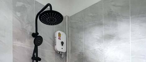 Ducha con cabezal de ducha de mano y panel de control en la pared.