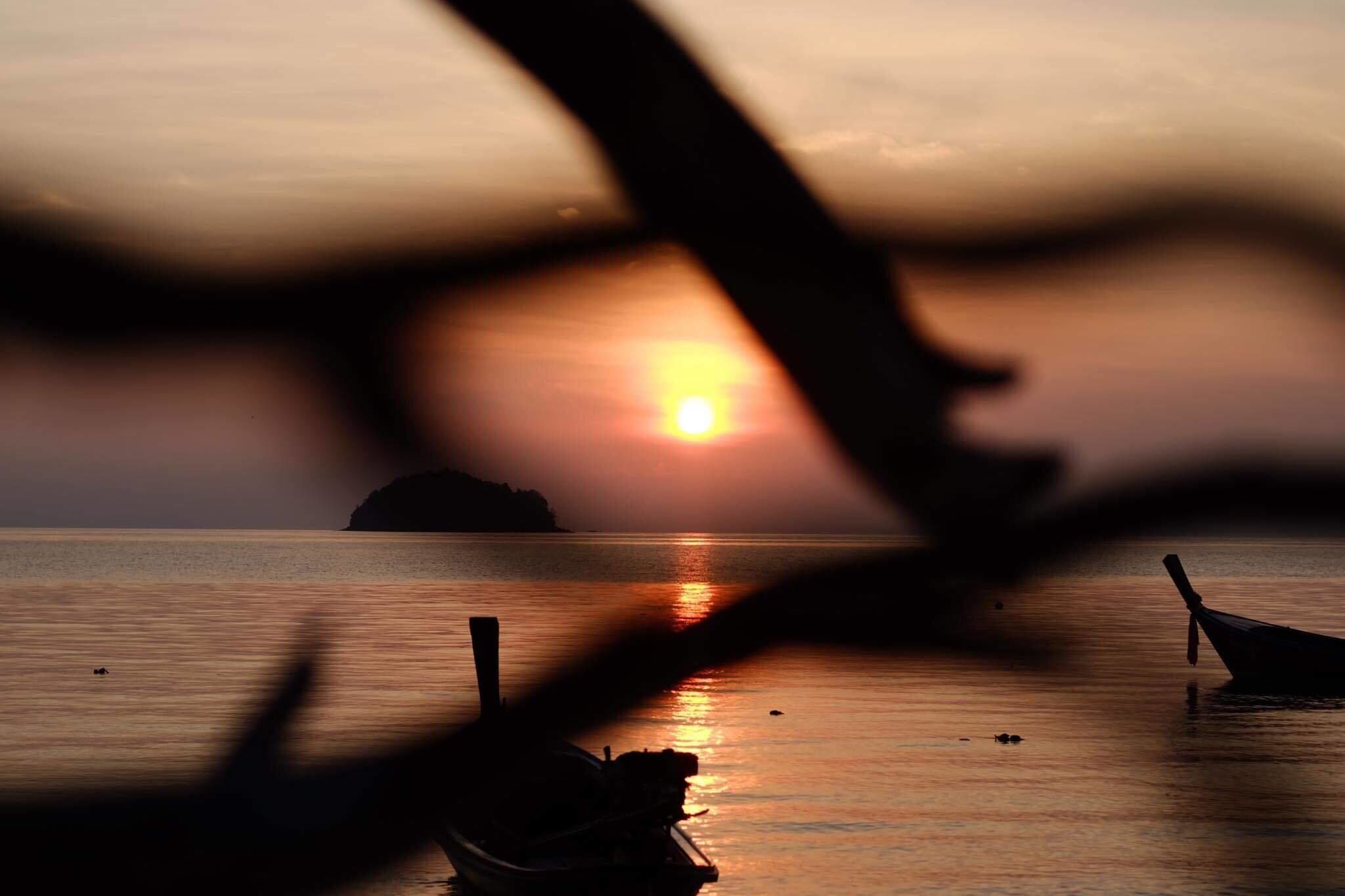 A boat on calm water with a sunset in the background.