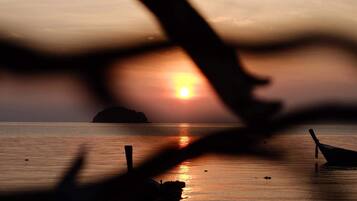 A boat on calm water with a sunset in the background.
