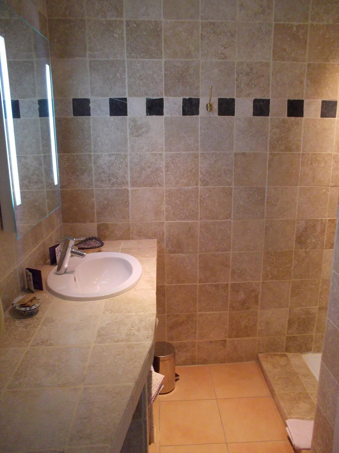 Une salle de bain avec un lavabo, un miroir et des murs carrelés.