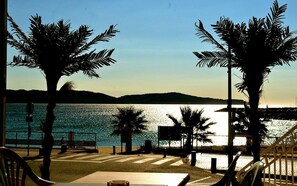 A beachside view with palm trees, a bench, and a view of the water. - Alizés Hôtel (Cavalaire-sur-Mer)