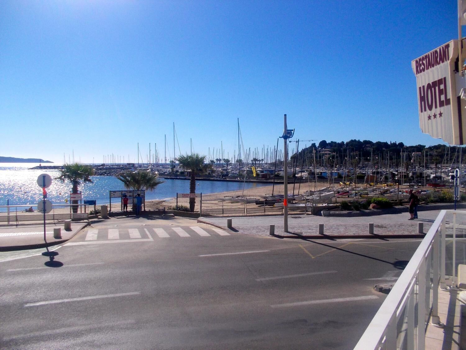 A marina with boats, a beach, and a sign for a restaurant and hotel.