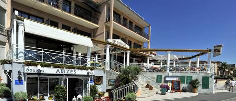 A hotel with a restaurant on the ground floor, a balcony with railings, and a staircase leading to the upper floors.